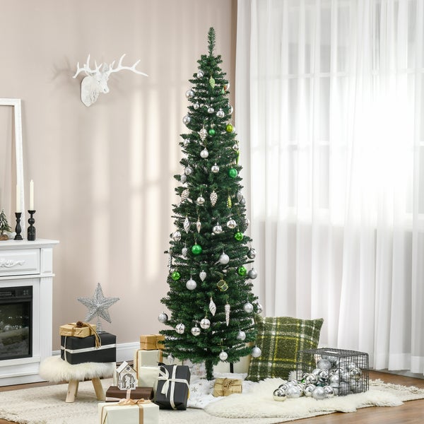 Schmaler künstlicher Weihnachtsbaum mit silbernem und grünem Schmuck in einem hellen Wohnzimmer mit Kamin und Geschenken.
