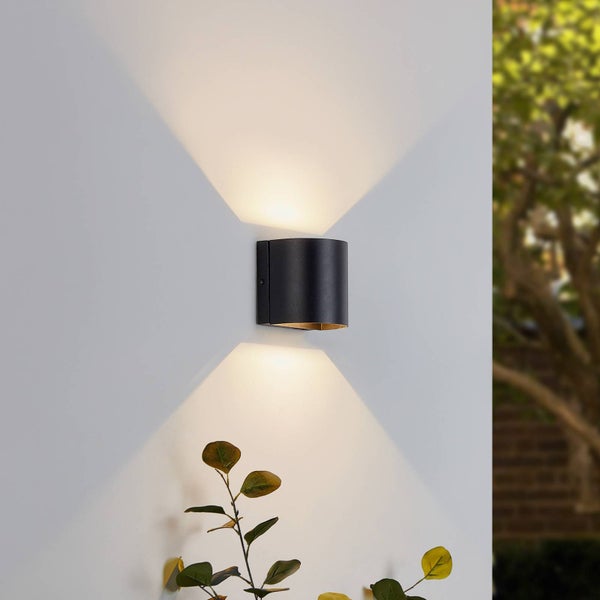 Moderne schwarze Außenwandleuchte mit Up-and-Down-Lichteffekt an einer Wand im Außenbereich.