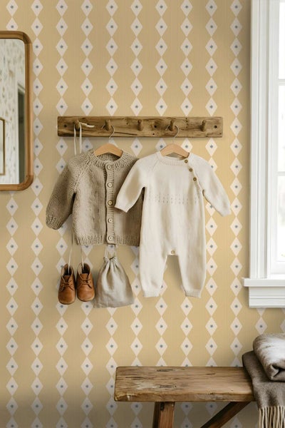 Kindertapete mit Rautenmuster und eingearbeiteten Sternen in einem Kinderzimmer mit Garderobe und aufgehängter Babykleidung