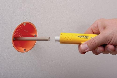 Hand mit Jokari Abisolierwerkzeug beim Abisolieren eines Kabels in einer Wanddose
