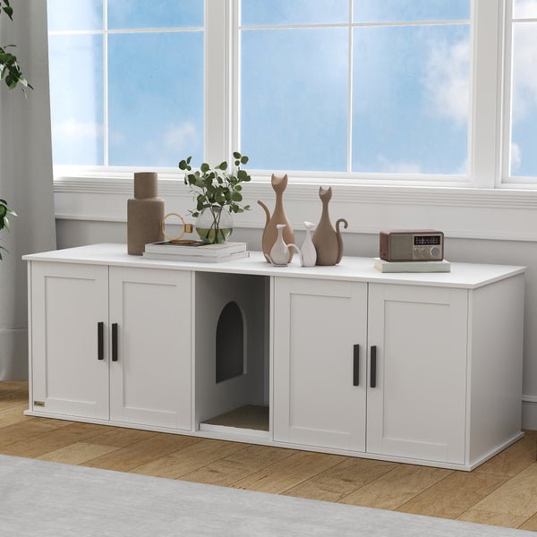 Weißes Katzenklo-Gehäuse in Sideboard-Optik mit vier Türen und zentralem Einstieg, dekoriert in einem hellen Wohnraum.
