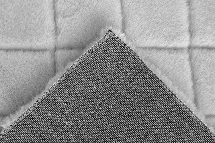 Detailaufnahme eines weichen Kunstfell-Teppichs mit quadratischer Steppung und rutschhemmender Rückseite.