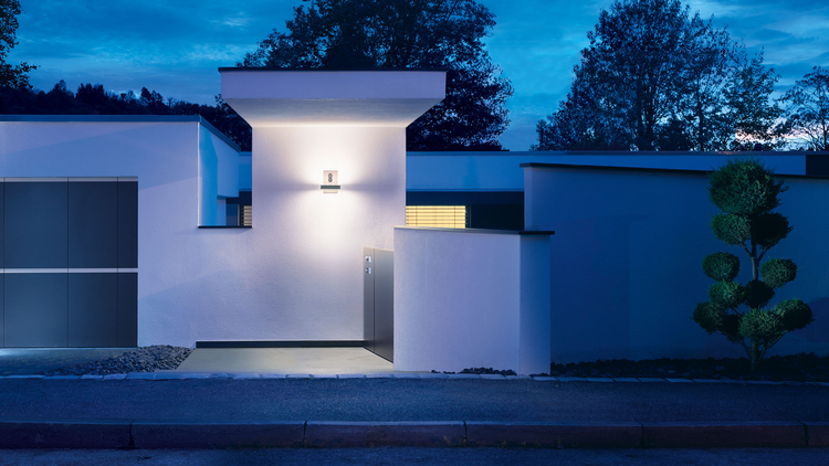 Moderne Hauswand mit beleuchteter Hausnummernleuchte Nummer acht bei Nacht, Außenbeleuchtung für den Eingangsbereich.