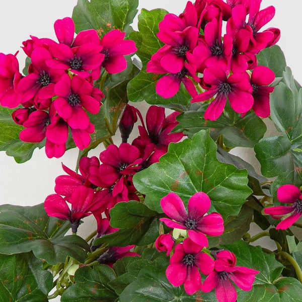 Künstliche Geranie mit pinken Blüten und grünen Blättern.