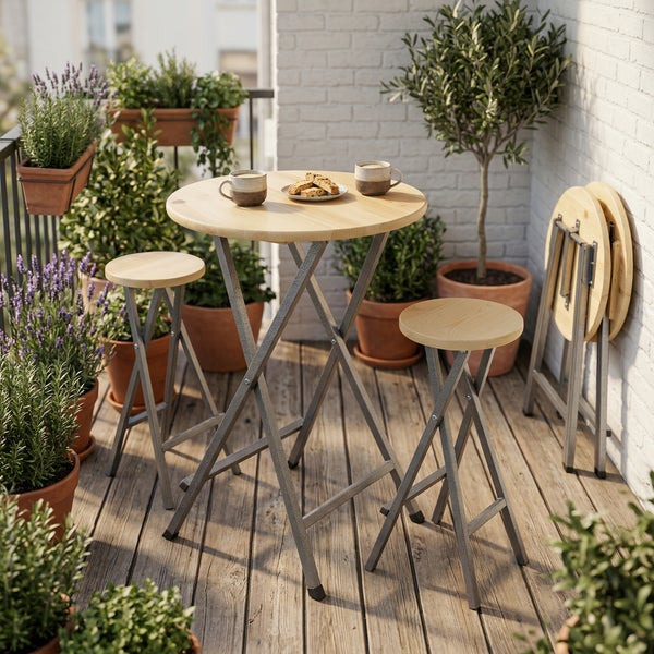 Stehtisch-Set aus Holz und Metall bestehend aus einem runden Tisch und zwei Barhockern, gedeckt mit Geschirr vor einer Steinwand.