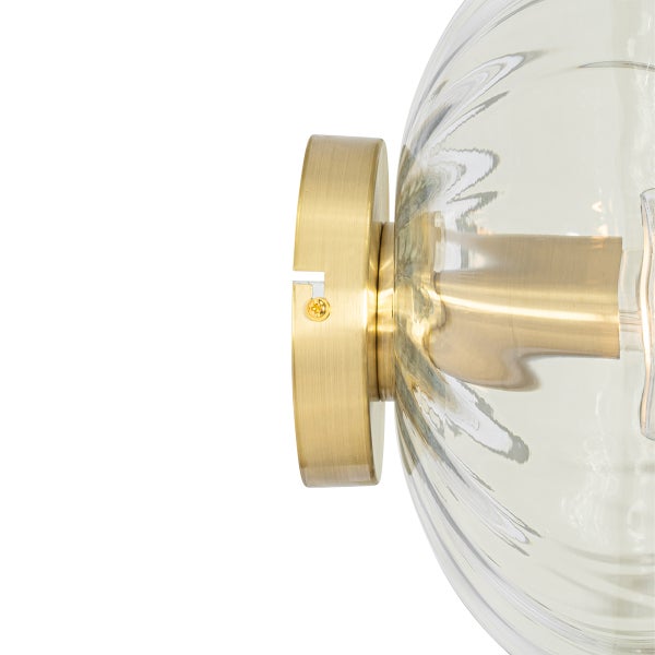 Nahaufnahme einer Wandleuchte mit einer transparenten, runden Glasabdeckung und einer Messinghalterung.