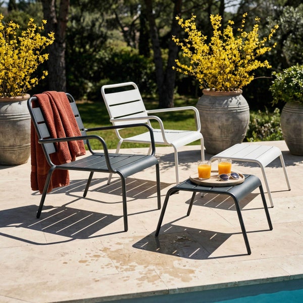 Moderne Gartenstühle und Hocker aus Metall in Anthrazit und Weiß auf einer Steinterrasse am Pool, mit gelb blühenden Pflanzen in großen Töpfen.