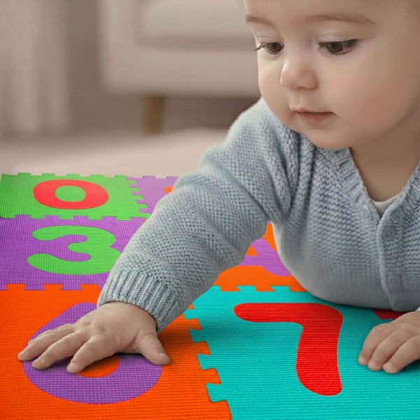 Ein Baby liegt auf einer bunten Puzzlematte aus Schaumstoff mit großen Zahlen.