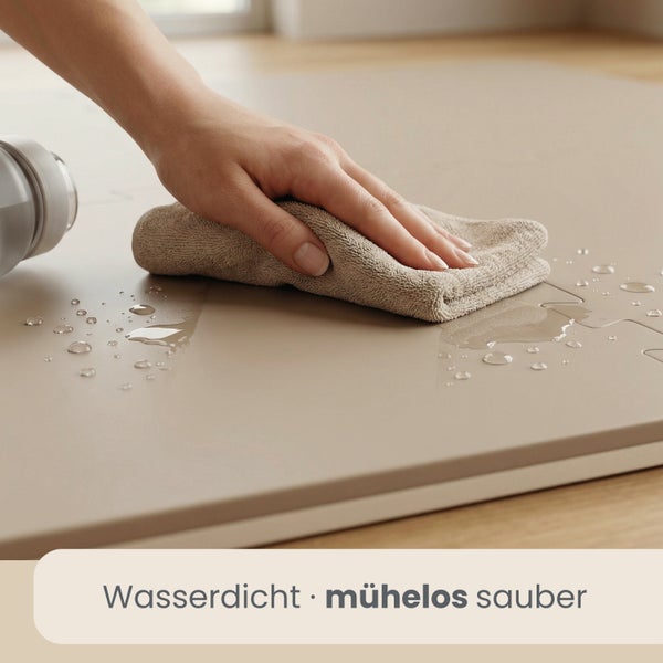 Hand wischt Wasser von einer wasserdichten und leicht zu reinigenden Oberfläche mit einem Tuch ab.