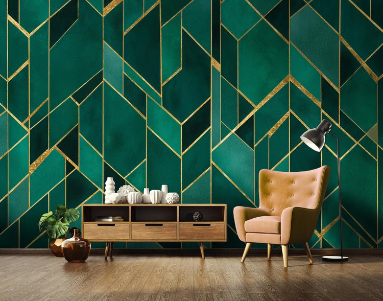 Wohnzimmer mit einem grünen Wandbild mit goldenen geometrischen Formen, einem Schrank, einer Stehlampe und einem Sessel.