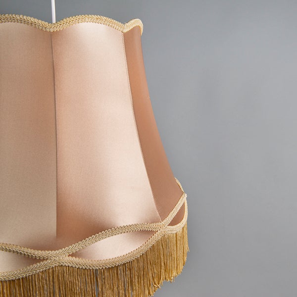 Klassischer Lampenschirm aus Stoff mit dekorativer Borte, gewelltem Rand und Fransenabschluss.