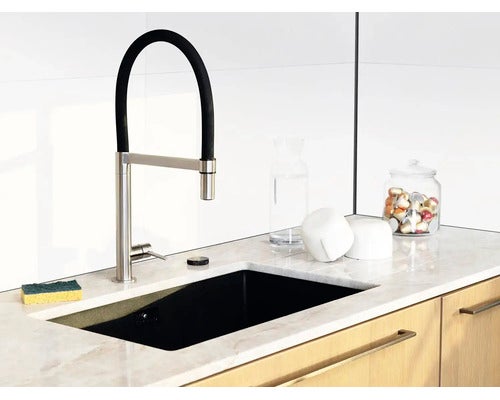 Moderne Küchenspüle mit schwarzer Armatur und flexiblem Auslauf auf einer hellen Marmorarbeitsplatte.