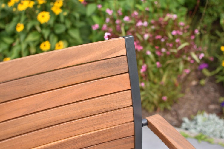 Detailansicht einer Gartenbank mit Holzlatten und Metallgestell vor floralem Hintergrund