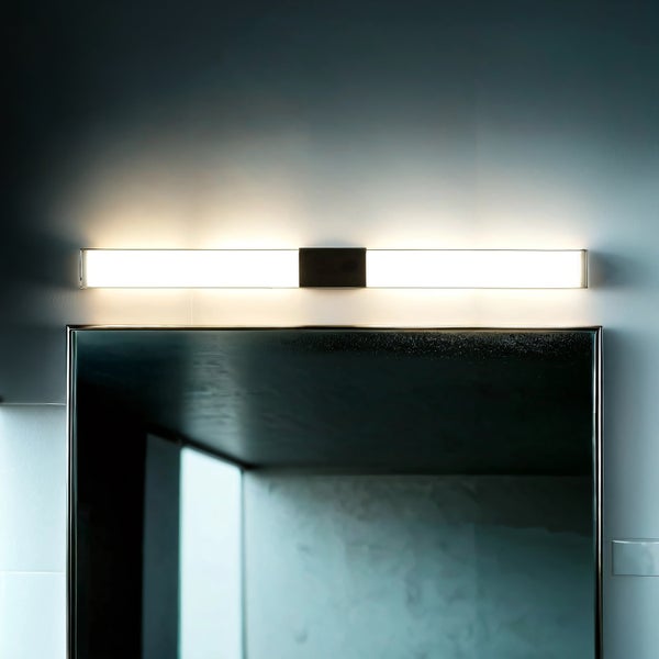 Moderne LED Spiegelleuchte in länglicher Form über einem Wandspiegel montiert mit gleichmäßiger Lichtverteilung für den Badezimmerbereich