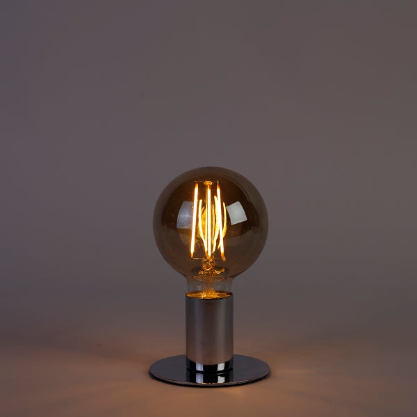 Eingeschaltetes LED Filament Leuchtmittel in Globusform mit rauchfarbenem Glas in einer runden Metallfassung.