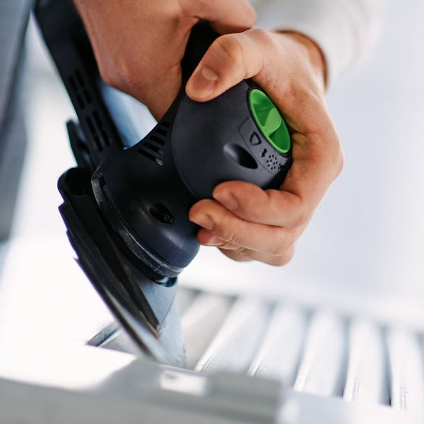 Detailaufnahme eines Handbandschleifers beim Bearbeiten eines Werkstücks