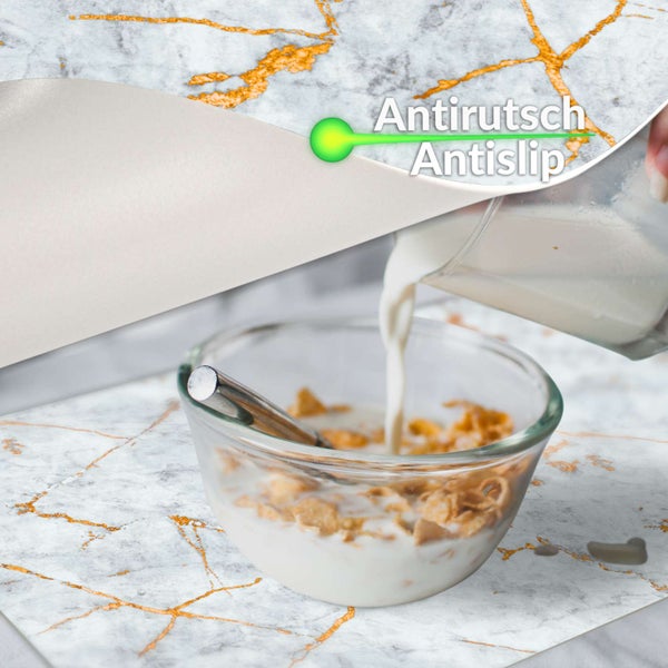 Antirutsch-Oberfläche in Marmoroptik mit goldfarbenen Adern, Schüssel mit Müsli auf der Unterlage, zeigt die rutschhemmende Eigenschaft.