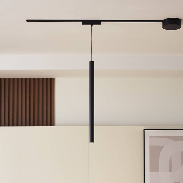 Moderne schwarze Pendelleuchte mit zylindrischem Schirm an einem Deckenschienensystem in einem hellen Raum mit Holzpaneelen.