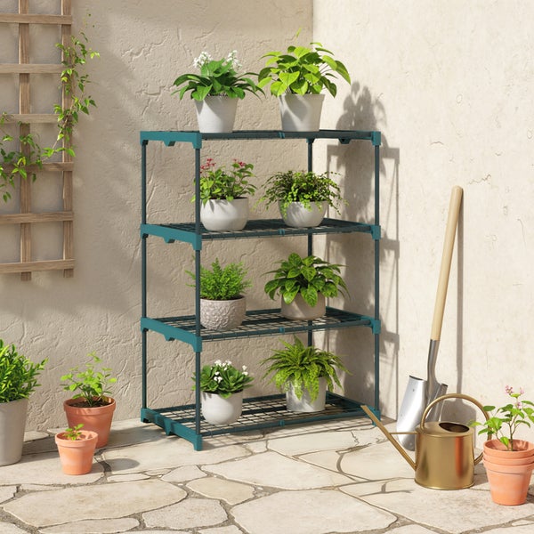 Vierstöckiges Pflanzenregal aus Kunststoff und Metall auf einer Terrasse mit Topfpflanzen, Spaten, Gießkanne und Holzspalier.