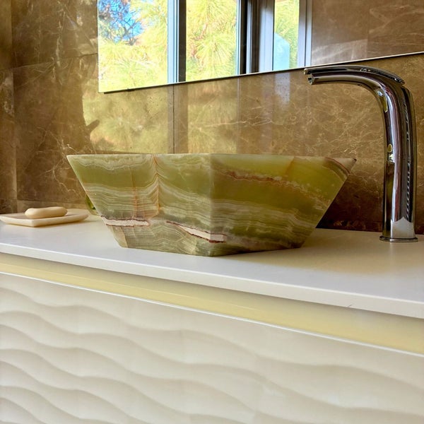 Modernes Badezimmer mit einem rechteckigen Aufsatzwaschbecken aus Naturstein, einer Chromarmatur und einem weißen Unterschrank mit Wellenstruktur.
