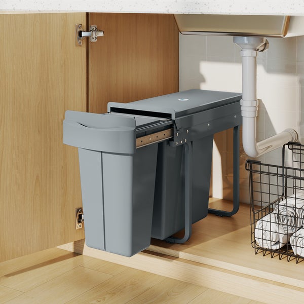 Frau wirft Abfall in einen ausziehbaren Mülleimer unter der Spüle in der Küche.