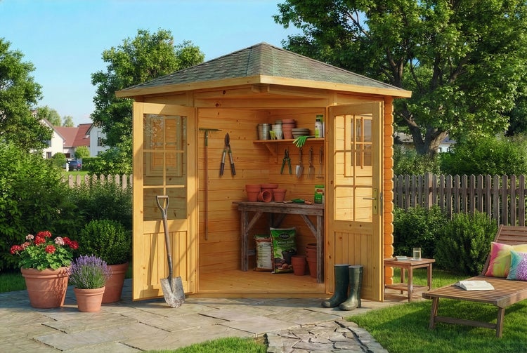 Eckgartenhaus aus Holz mit geöffneten Doppeltüren, Inneneinrichtung mit Werkbank, Regalen und Gartengeräten auf einer Steinterrasse.