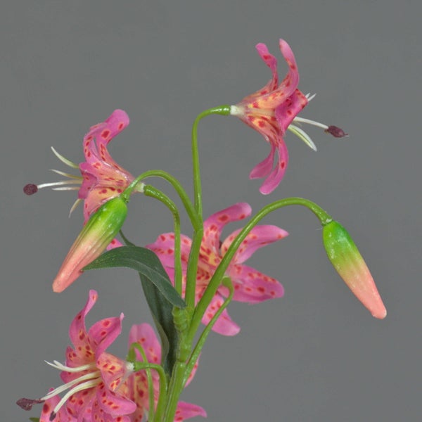 Künstlicher Lilienzweig mit pinkfarbenen, gepunkteten Blüten und grünen Blättern.