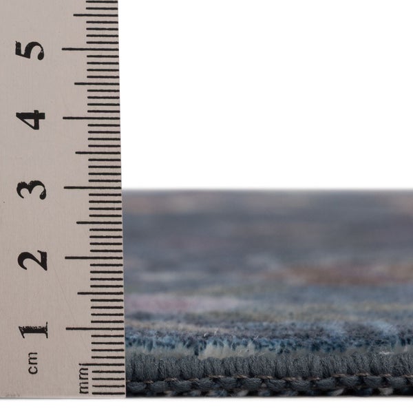 Messung der Florhöhe eines Teppichs mit einem Lineal, die eine Dicke von circa 8 bis 9 Millimetern zeigt.