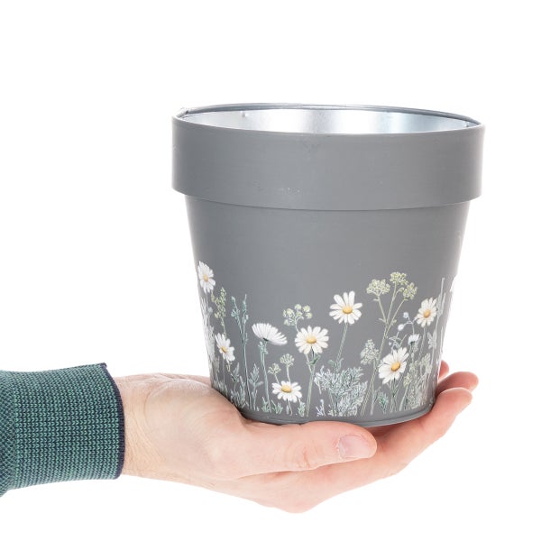 Grauer Blumenübertopf aus Zink mit weißem Gänseblümchen-Dekor.