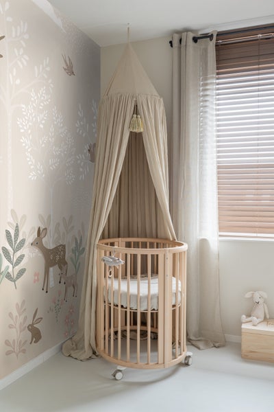 Kinderzimmer mit rundem Kinderbett, Baldachin und Tiermuster-Tapete