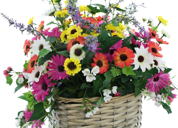 Dekoratives Blumenarrangement im Korb auf Fensterbank