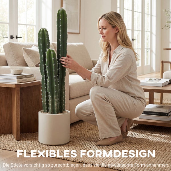 Frau richtet die biegsamen Stiele eines künstlichen Kaktus in einem modernen, hellen Wohnzimmer mit beigem Sofa und Holzmöbeln aus.