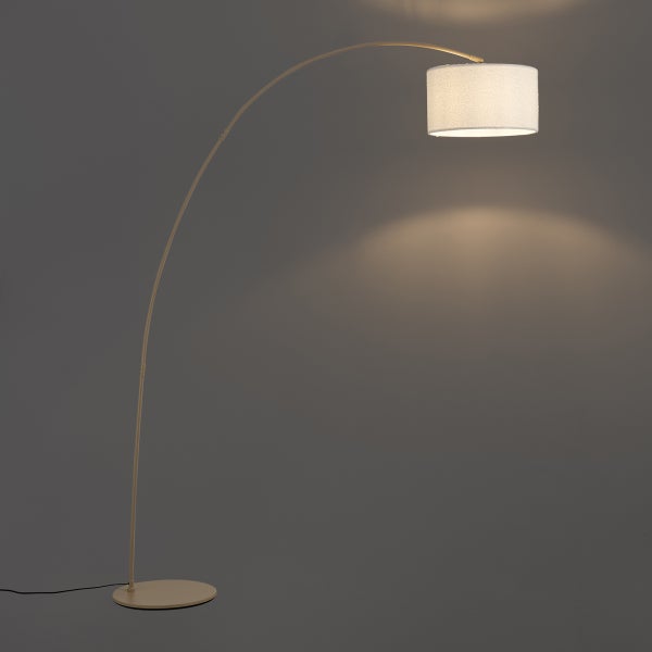 Bogenstehlampe mit gebogenem Metallarm und zylindrischem Textilschirm, eingeschaltet mit warmem Licht.