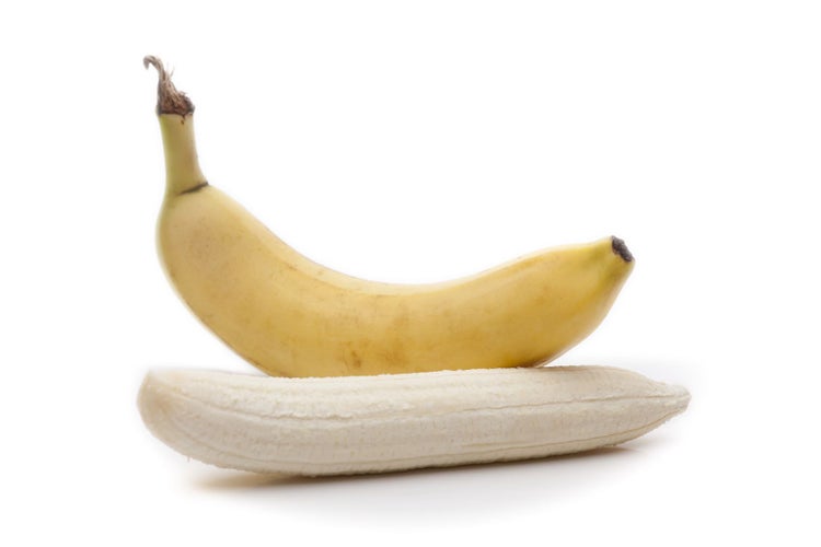 Eine ganze Banane mit Schale und eine geschälte Banane.