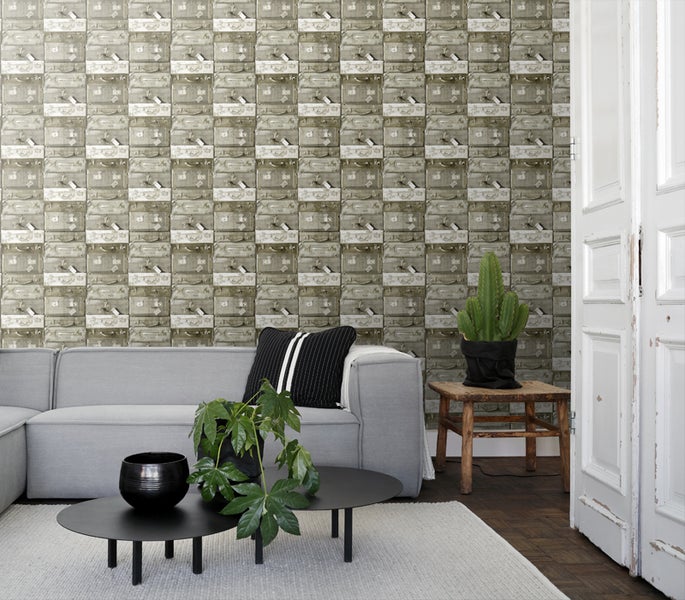 Wohnzimmer mit Tapete im Stil gestapelter Koffer, graues Sofa und Dekoration.