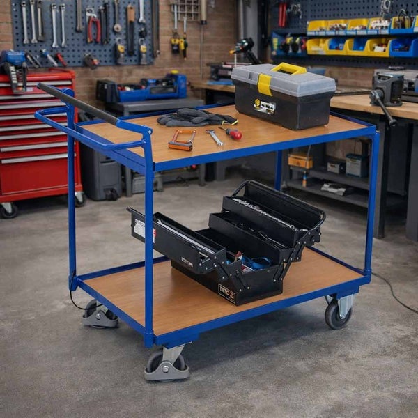 Werkstattwagen mit zwei Holzböden in einer Werkstatt. Auf den Böden befinden sich Werkzeugkästen und Werkzeuge. Der Wagen hat vier Rollen.
