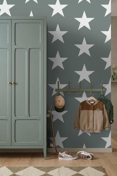 Kinderzimmer mit grauer Sterntapete, grünem Kleiderschrank und Wandgarderobe mit Kinderjacke und Rucksack.
