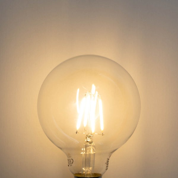 Eingeschaltete LED-Globelampe aus Klarglas mit sichtbaren Filamenten.