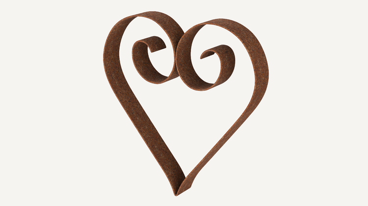 Dekoratives Herz aus Metall im Gartenbeet.