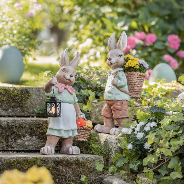 Zwei Hasenfiguren mit Laterne und Blumenkorb als Gartendekoration