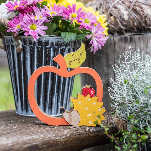 Dekoration mit Apfel- und Igelmotiven sowie Blumenschmuck in einem Metalleimer
