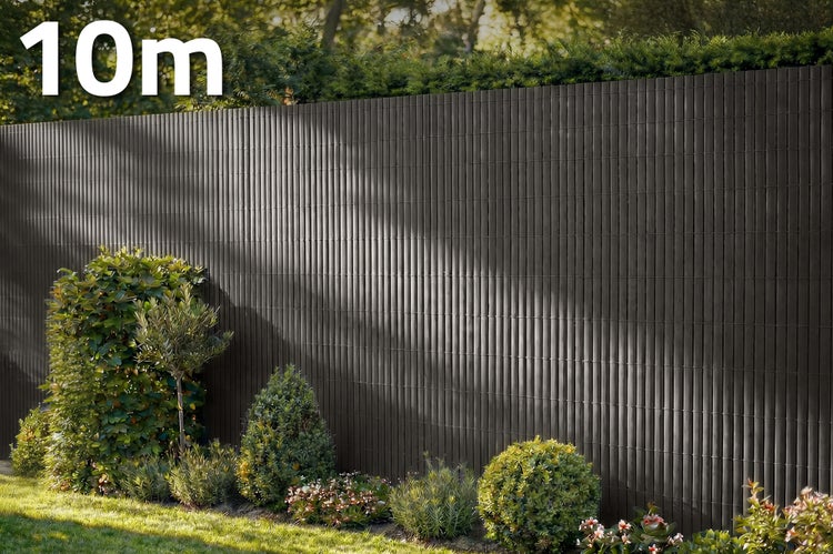 PVC Sichtschutzmatte in Lamellenoptik als Sichtschutz für den Garten mit einer Länge von 10 Metern vor einer Gartenbepflanzung.