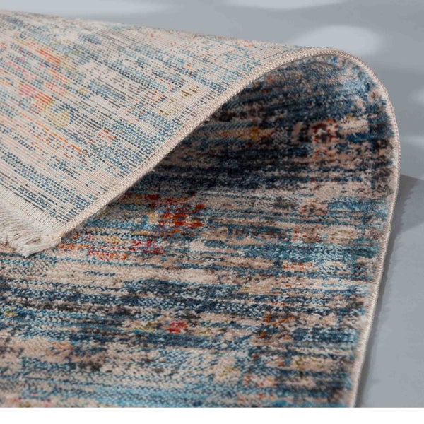 Kurzfloriger Webteppich mit abstraktem Muster in Blau und Creme, umgeschlagene Ecke zeigt die gewebte Rückseite.