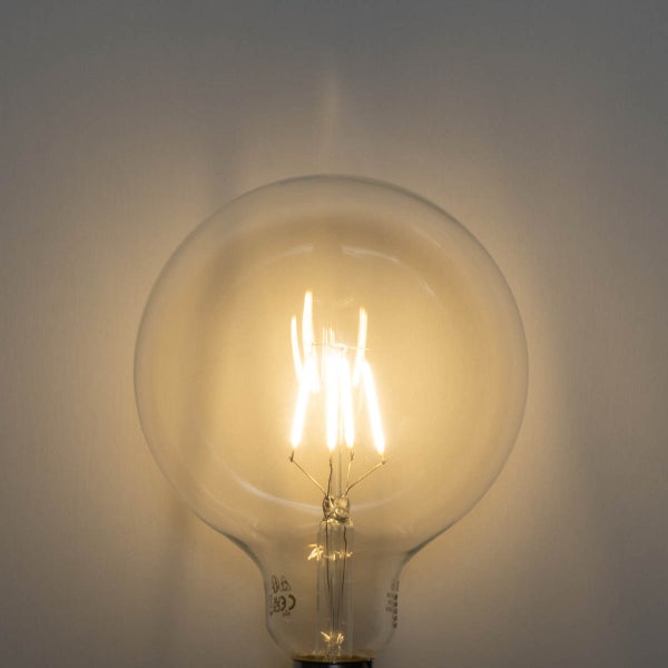 Eingeschaltetes LED-Filament-Leuchtmittel in Globusform aus klarem Glas mit sichtbaren Leuchtfäden.