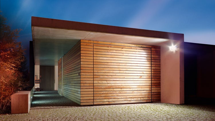 Moderne Hausfassade mit Holzelementen und Außenbeleuchtung