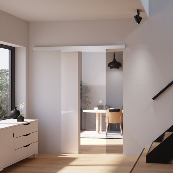 Moderne Glasschiebetür mit satiniertem und klarem Glas in einem hellen Wohnraum mit Blick auf das Esszimmer.