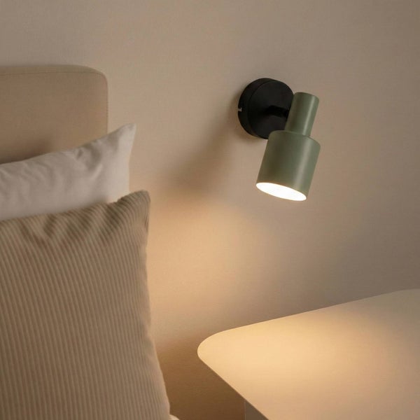 Grüne Wandleuchte neben einem Bett und einem Nachttisch