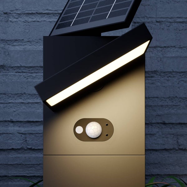 Solar-LED-Wandleuchte mit Bewegungssensor, Solarpanel und schwenkbarem Lichtbalken vor einer Ziegelwand.