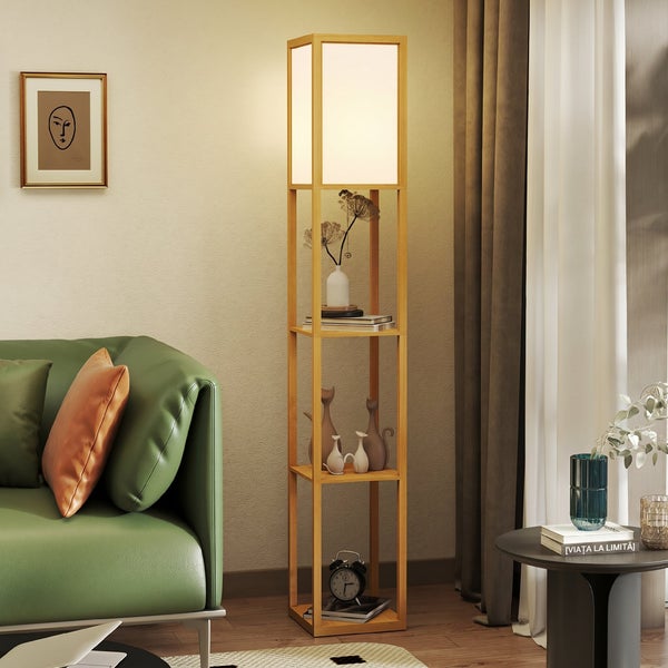 Moderne Stehlampe aus Holz mit integrierten Regalböden in einem hellen Wohnzimmer neben einem grünen Sofa.