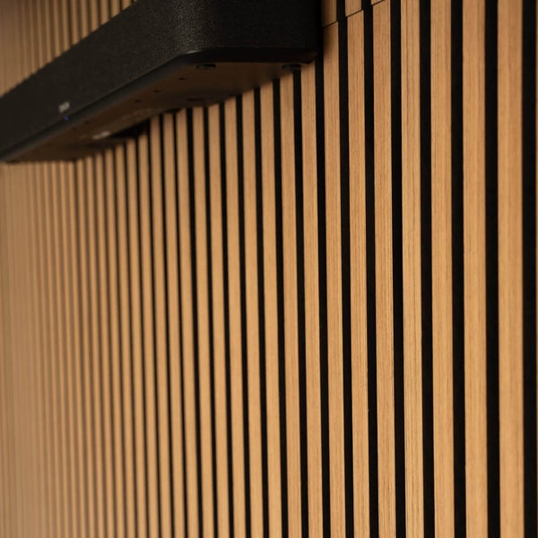 Akustikpaneel mit vertikalen Holzlamellen aus Eiche auf Filz mit einer montierten Soundbar.